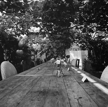 A warm, inviting long wooden table set outdoors with candles and fresh seasonal dishes ready for a feast.