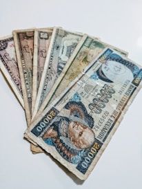 An assortment of old Indian coins and banknotes spread out on a cloth.