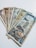 A collection of vintage currency notes fanned out on a flat surface. The notes display a variety of colors, designs, and denominations, suggesting they are from different historical periods or countries.