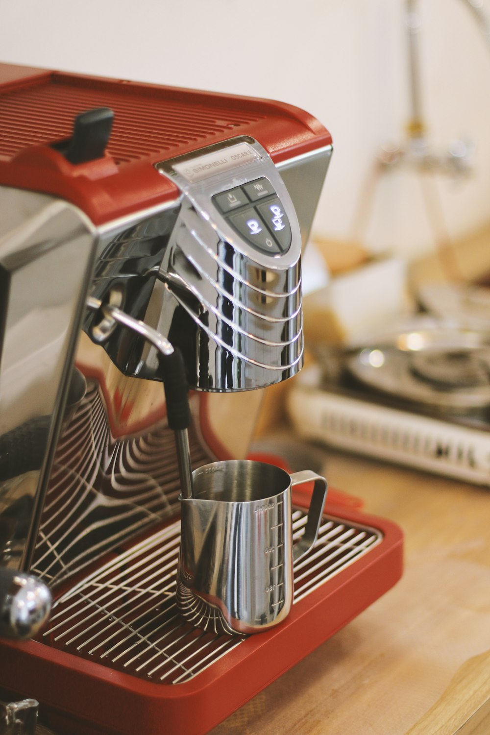 cup near red and gray stainless steel coffee maker