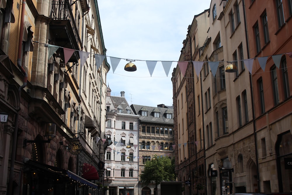 a narrow city street with buildings and bunting