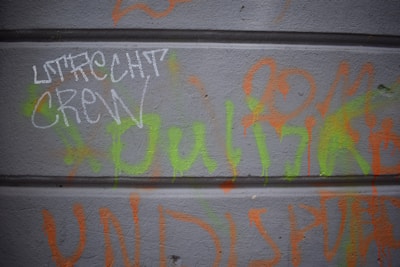 Crew members working together to clean a graffiti-covered brick wall.