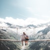 man and woman sitting on hanging bridge at daytime