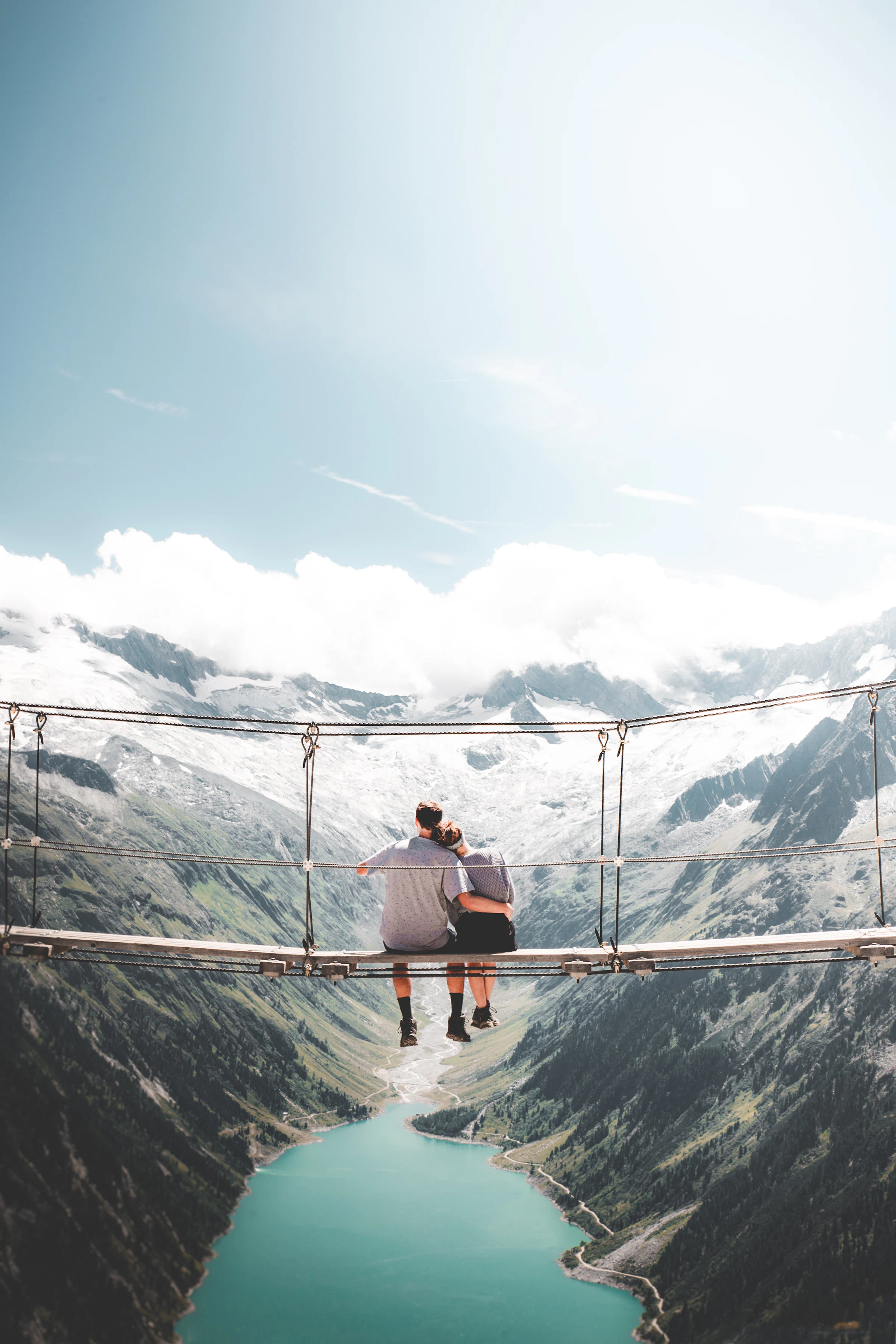 Two travellers sitting on a hanging bridge in the forest