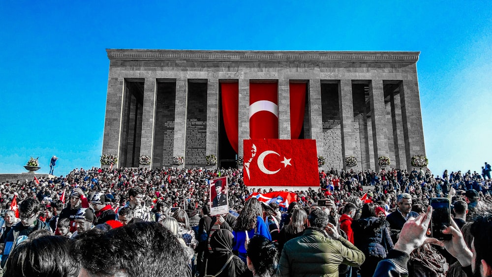 昼間、トルコ国旗を掲げた建物付近の人々の群れ