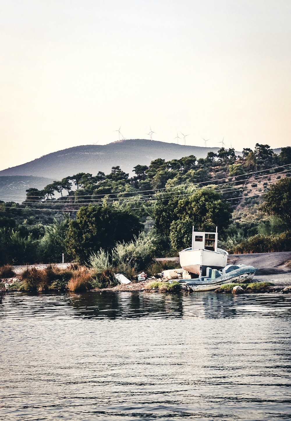 Weißes Boot in der Nähe von Felsen mit Blick auf den Berg während des Tages