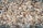 A large pile of chopped firewood pieces, neatly stacked and closely packed together. The wood displays various shades of brown, beige, and tan, highlighting the natural textures and grain patterns.