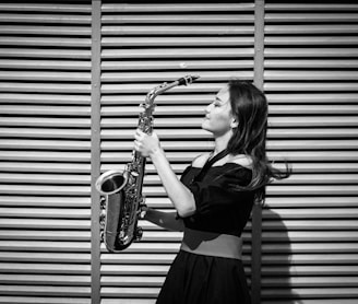 grayscale photography of woman holding saxophone