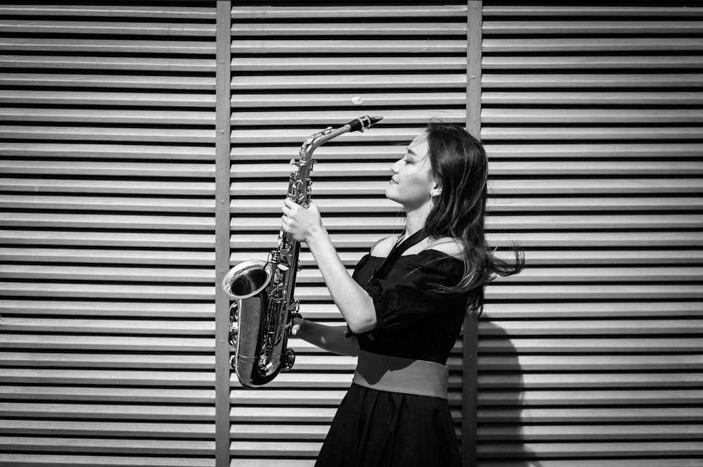 grayscale photography of woman holding saxophone