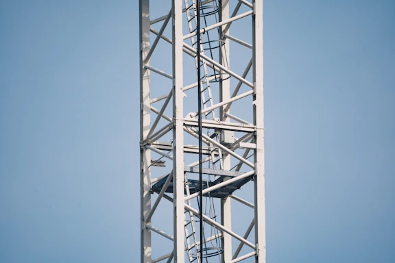 A close-up of steel beams being assembled on a construction site under a clear sky.