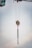A crane's lifting mechanism is suspended mid-air with extended metal chains hanging down. The background features a soft, cloudy sky.
