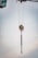 A crane's lifting mechanism is suspended mid-air with extended metal chains hanging down. The background features a soft, cloudy sky.