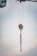 A crane's lifting mechanism is suspended mid-air with extended metal chains hanging down. The background features a soft, cloudy sky.