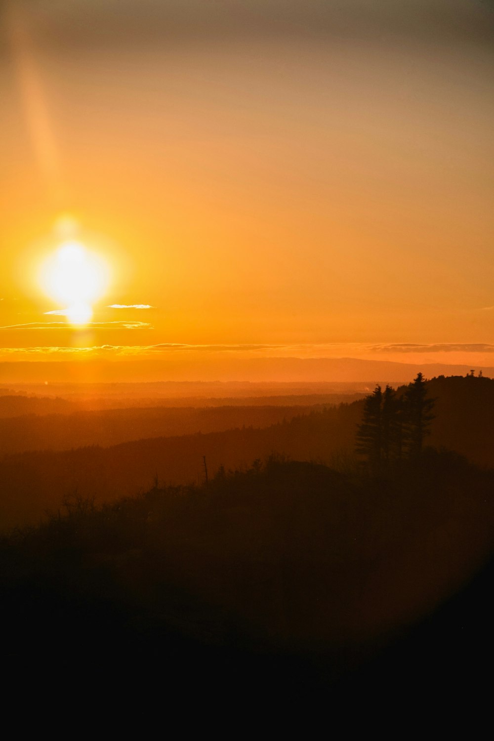 the sun is setting over the hills and trees