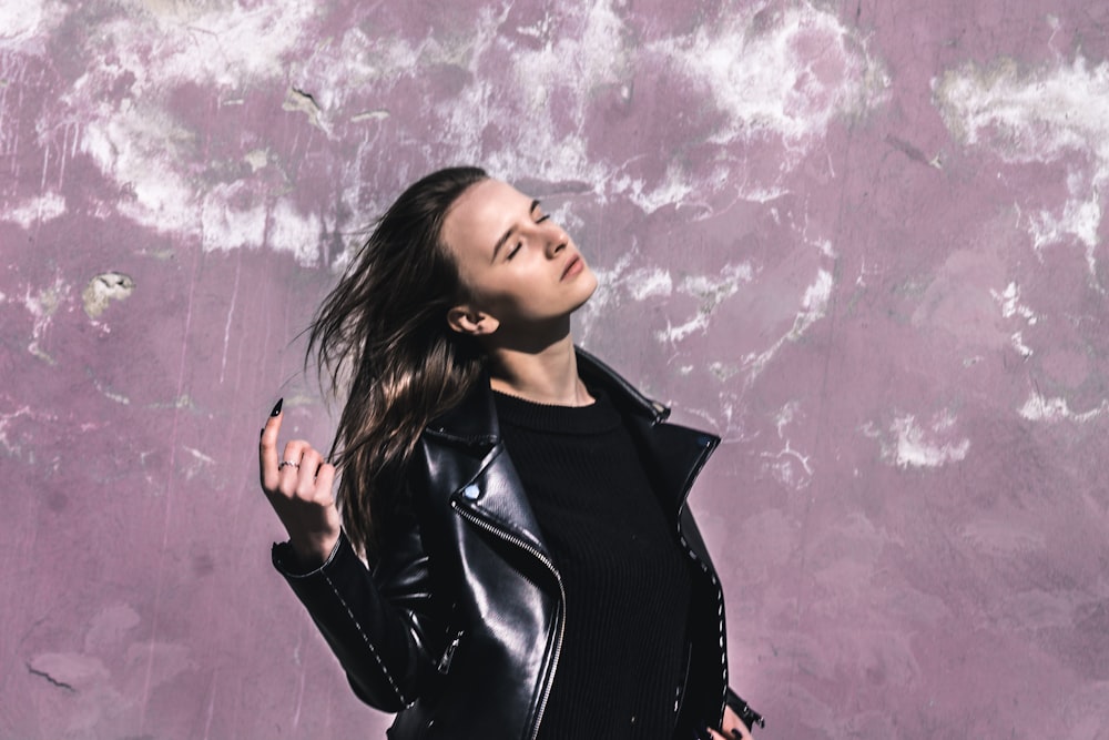 woman waving her hair standing in front of purple wall