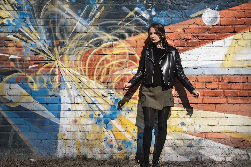 woman wearing black leather jacket standing near wall