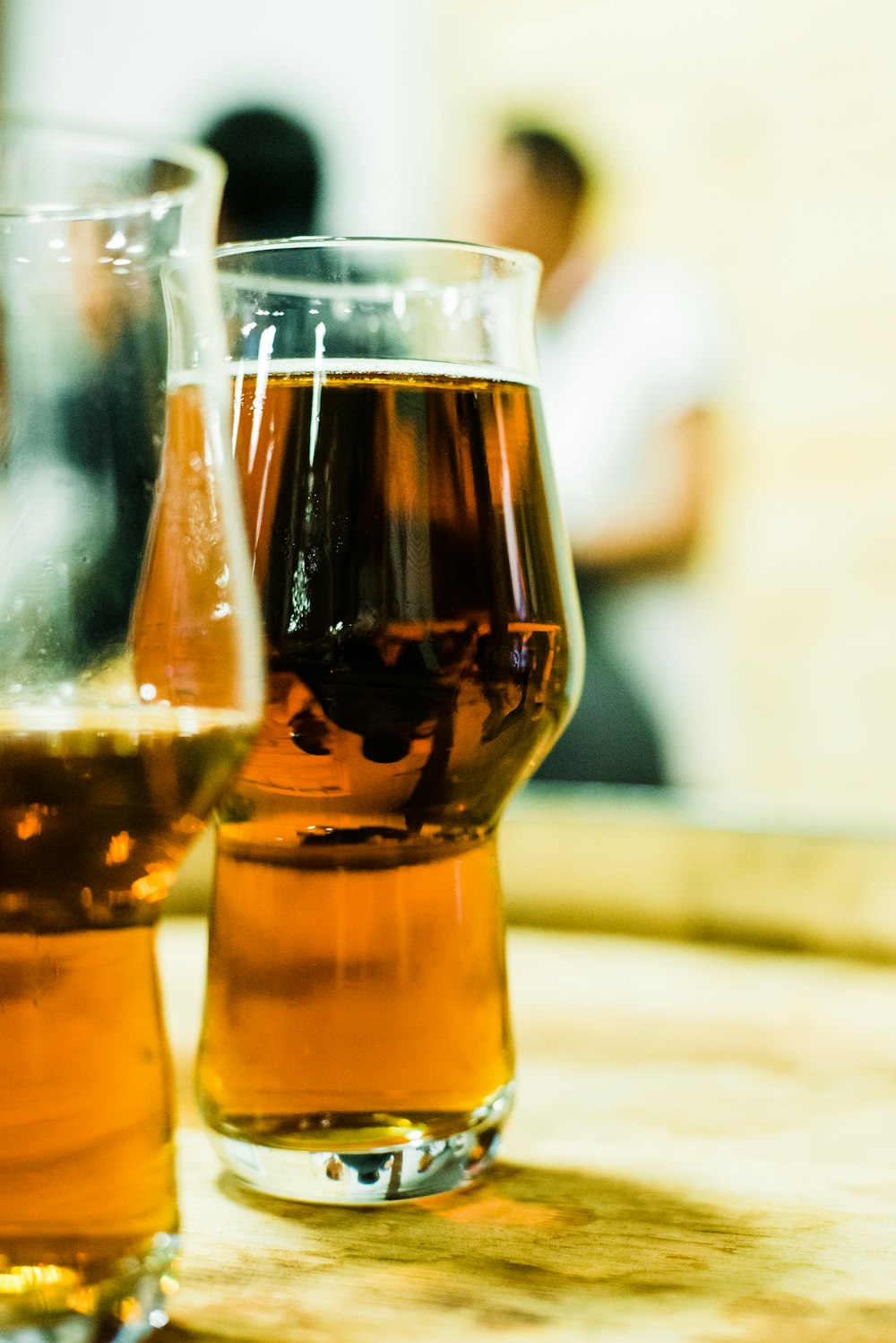 two glasses of beer sitting on top of a wooden table