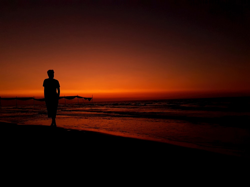 silhouette photography of person standing on seashore