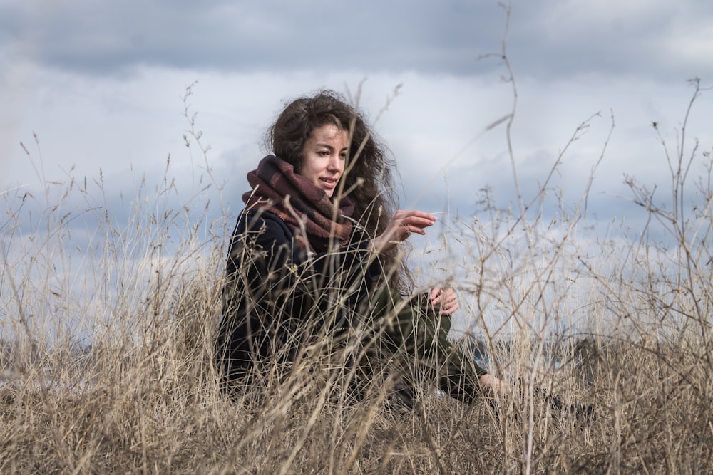 a woman sitting in a field of tall grass