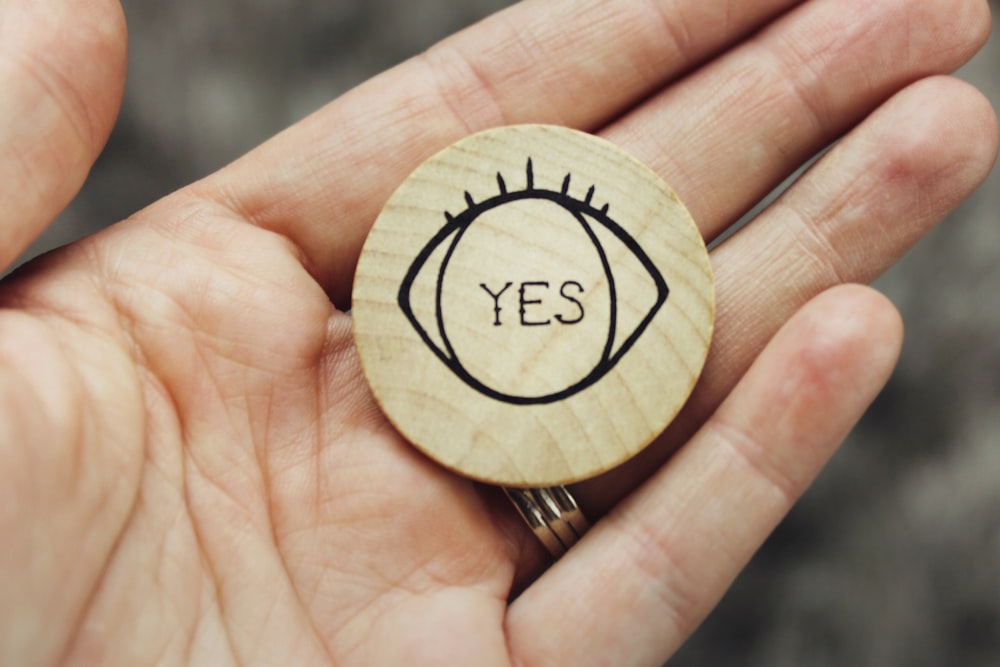 Una persona sosteniendo un anillo de madera con la palabra sí en él