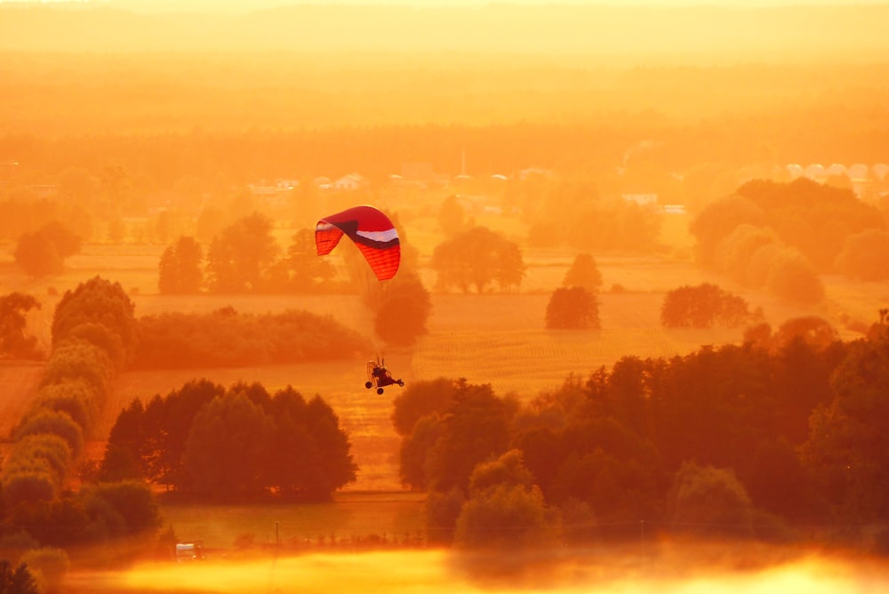 a person is parasailing over a field at sunset
