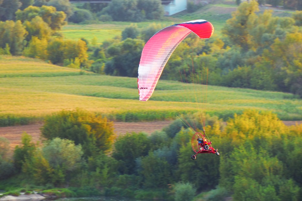 vehicle with fan on it's tail and red parachute in mid air during day