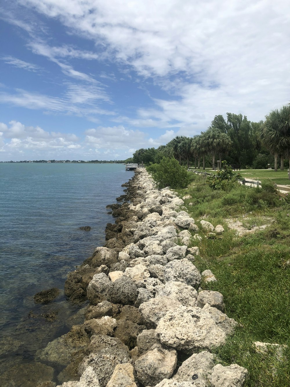 rock formations near seashore under blue and white skies during daytime