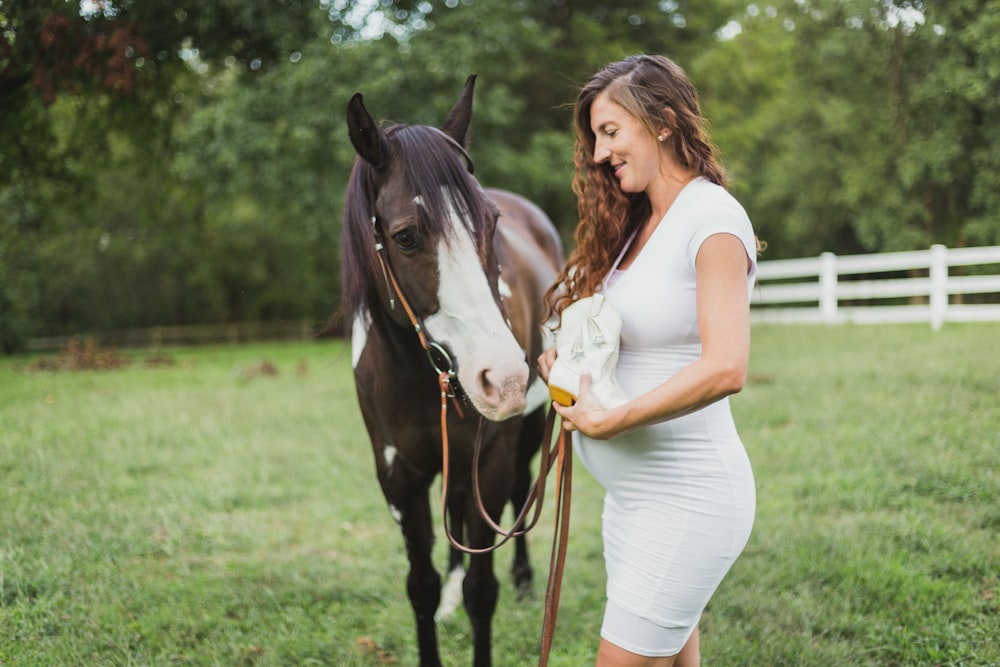 pregnant woman standing beside horse