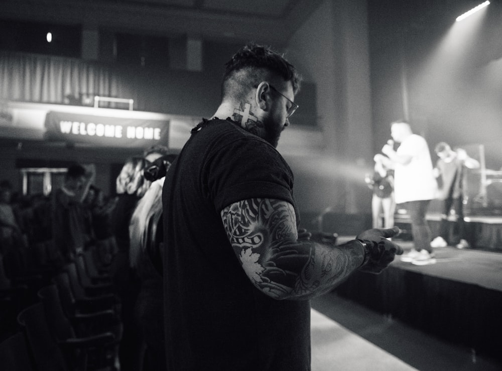 grayscale photo of man standing and watching concert