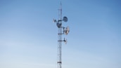 An outdoor setup of microwave antennas on a tower against a blue sky.