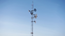 An outdoor setup of microwave antennas on a tower against a blue sky.