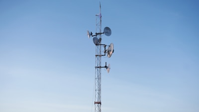 Satellite communication system antenna against a clear blue sky.