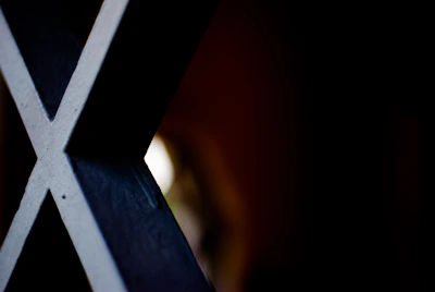 Close-up of a sharp ‘X’ logo illuminated with a subtle metallic glow on a dark textured surface.