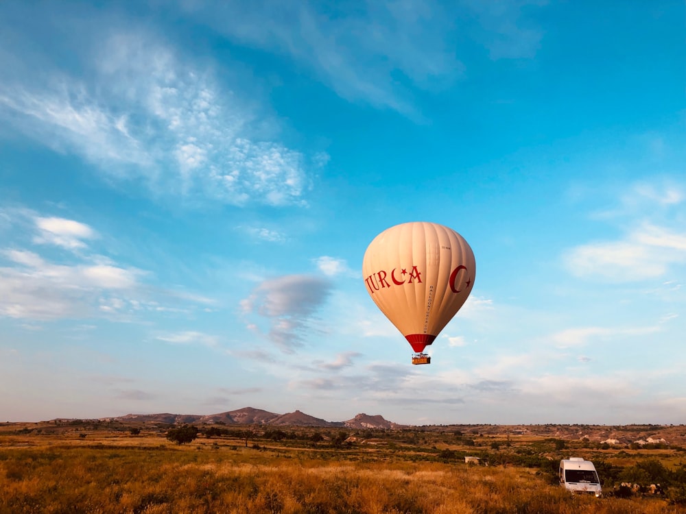 hot air balloon in mid air above vehicle during day