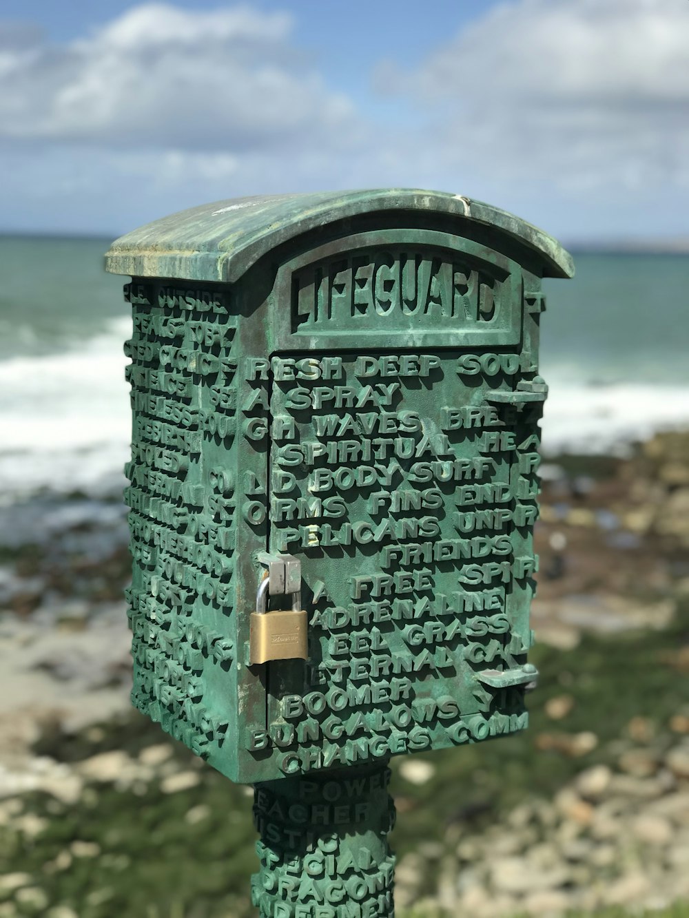 a close up of a green mailbox near the ocean