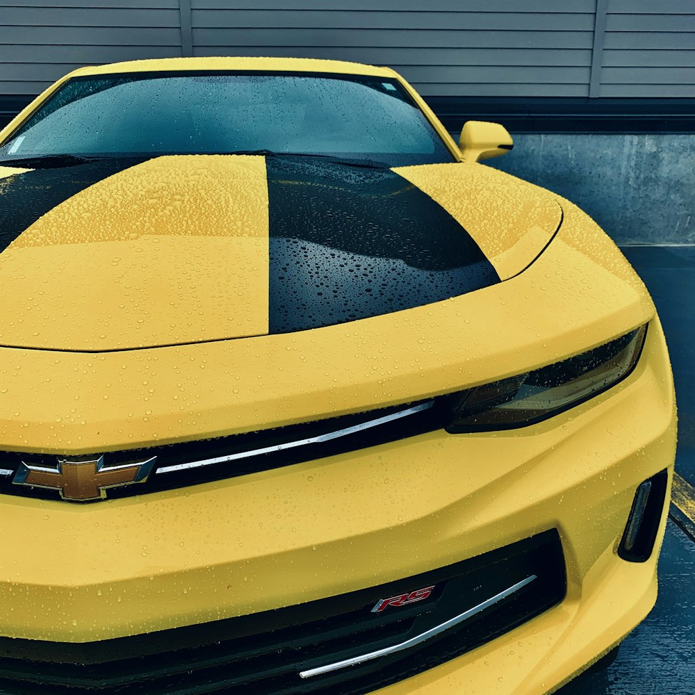 yellow and black Chevrolet car parked in front of wall