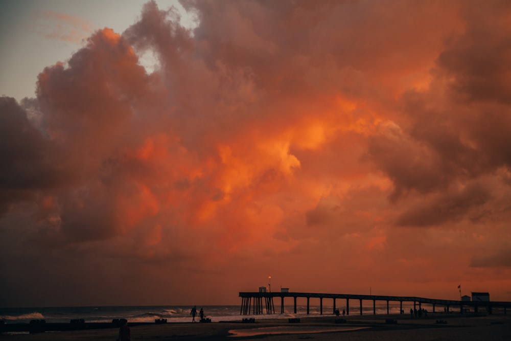 Stranddock mit Blick auf das Meer unter orangefarbenem Himmel