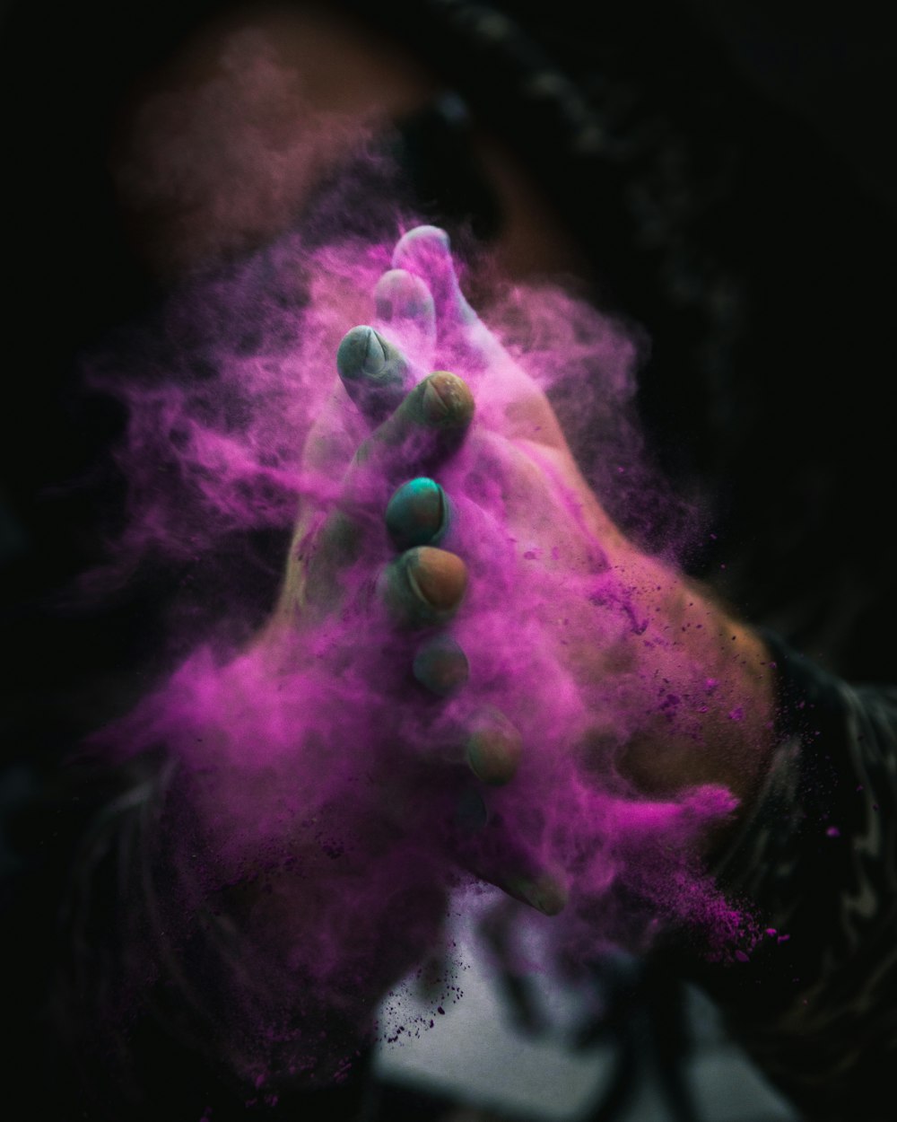 person with colored powders on hands