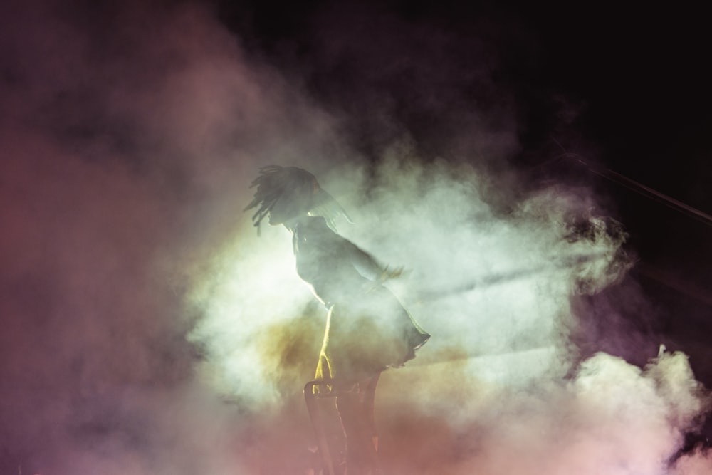 a person standing on a stage with smoke coming out of it