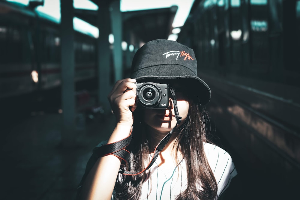 mulher usando chapéu preto do balde segurando a câmera