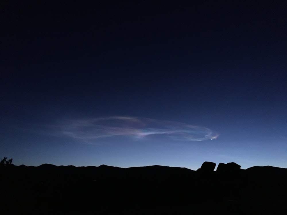 a dark sky with a few clouds in the distance