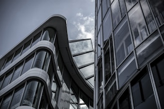 Modern architecture featuring two large glass and steel buildings with sleek, curved designs under a cloudy sky.