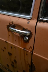Close-up of rust spots being treated with specialized tools on a car door.