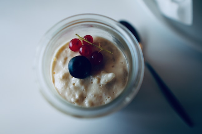 Close-up of a creamy avocado chocolate mousse in a glass jar with a beige background