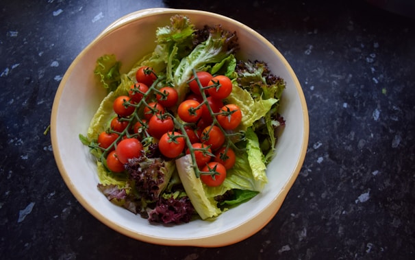 A colorful bowl of mixed greens salad topped with juicy cherry tomatoes and a light vinaigrette.