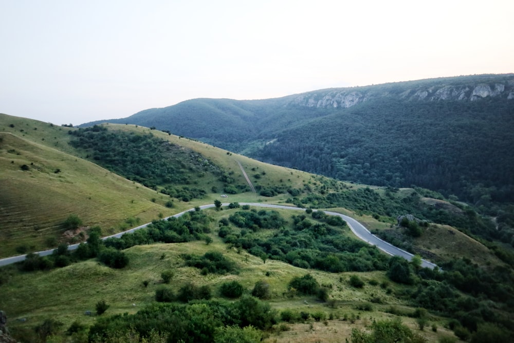 a winding road winding through a lush green valley