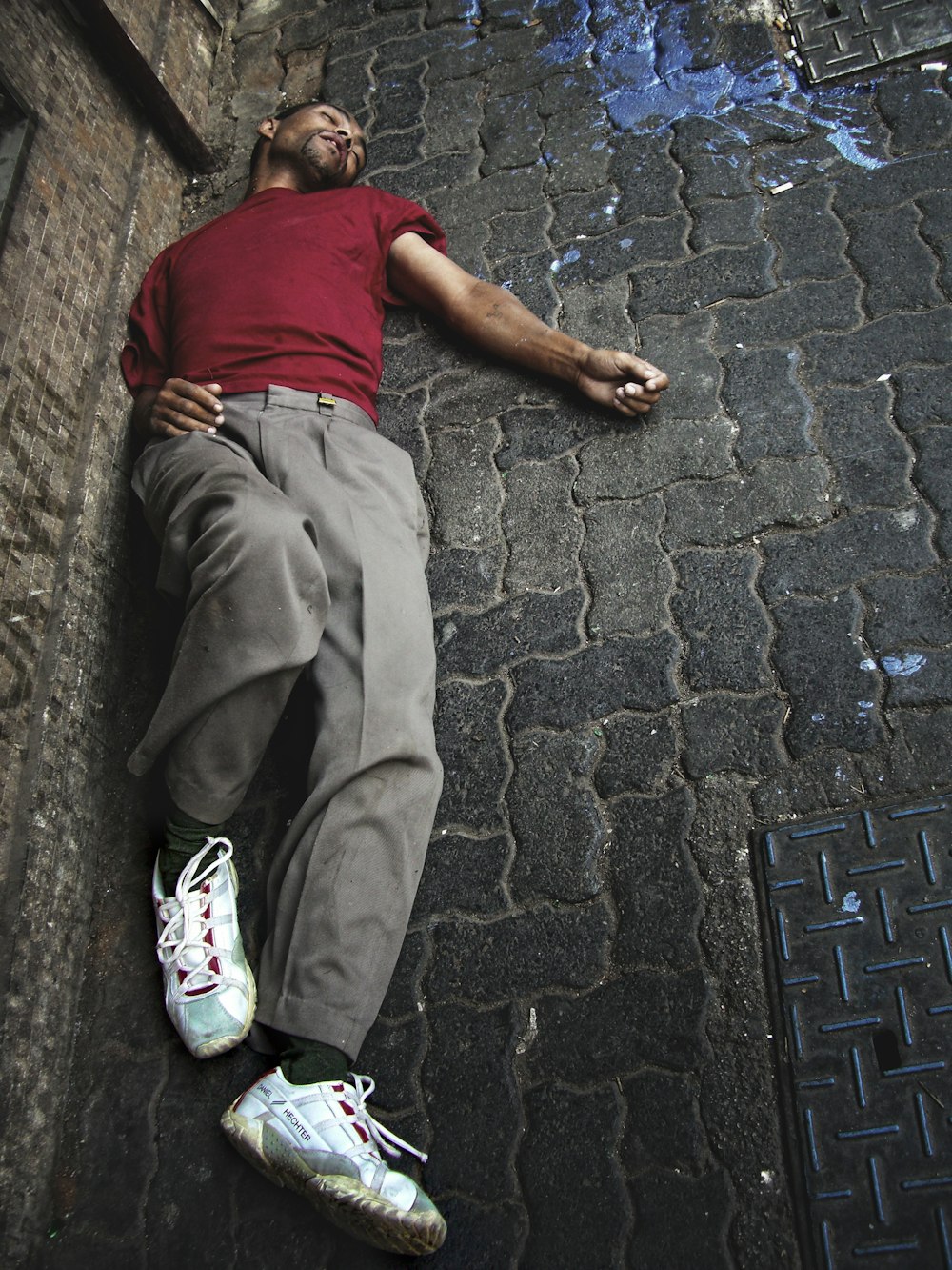 um homem deitado no chão ao lado de um hidrante