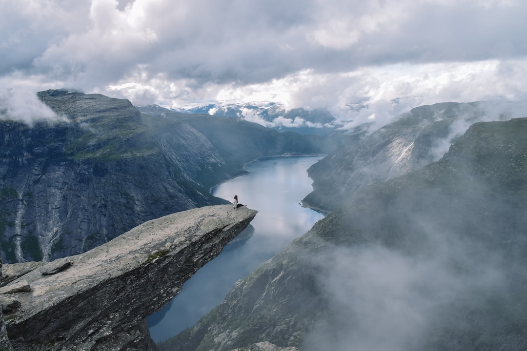 person at a gray cliff overlooking a river