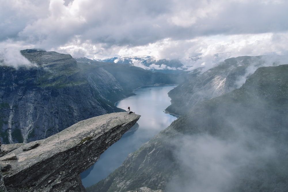 Person an einer grauen Klippe mit Blick auf einen Fluss