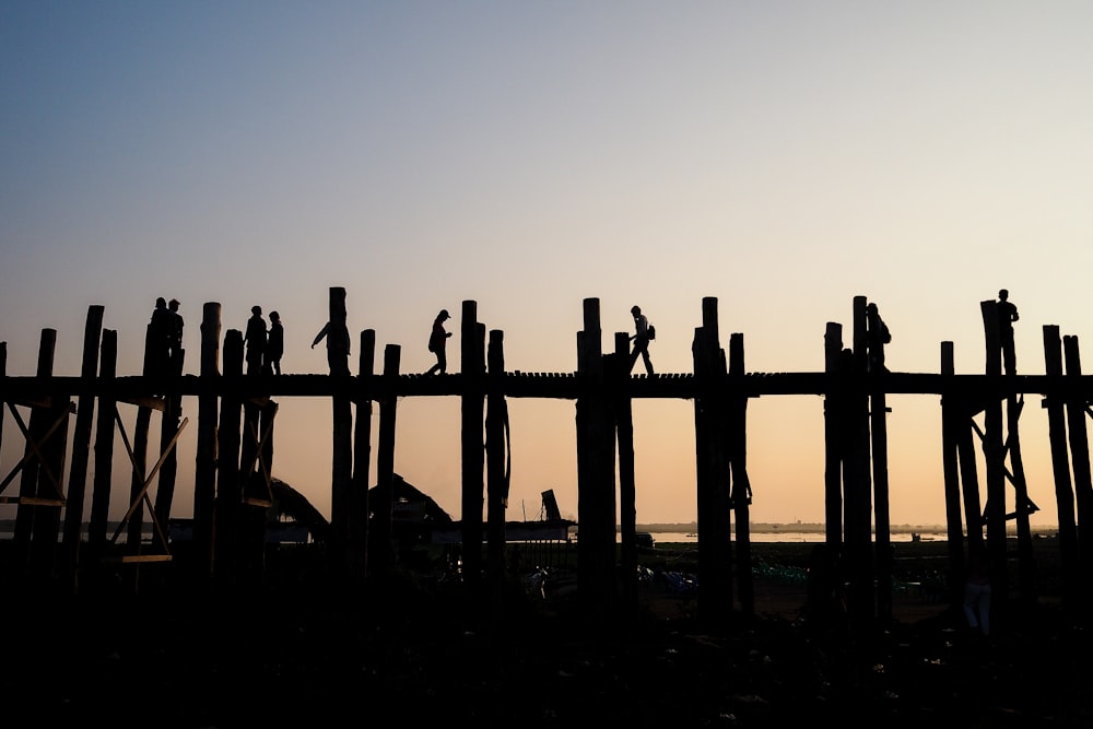 a group of people walking across a wooden bridge